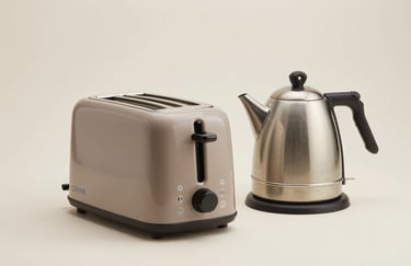 Clean studio photography of a modern toaster and kettle set in muted taupe on a soft off-white surface, representing high-quality South American / Brazilian home staples.