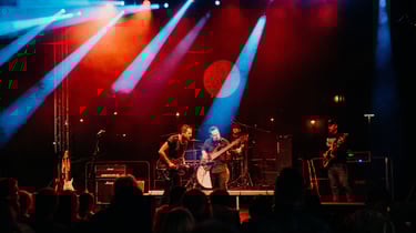 A lively band performing on stage with vibrant lighting in a night setting.
