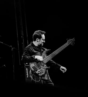 A striking black and white image of Jozef Bobula onstage playing bass during a live concert.