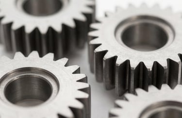 Macro photography of perfectly machined steel automotive gears. Sharp focus, clean lighting emphasizing the texture and precision, with a cool professional color palette including #F9F9F9 and dark steel #1A1A1A.