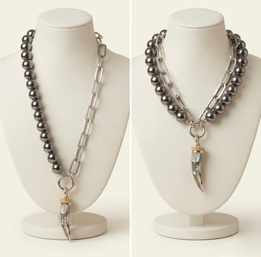 Silver chain and hematite bead necklaces with shell horn pendants on white jewelry displays.
