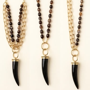 Layered gold chain necklace with brown agate beads and a black horn pendant.