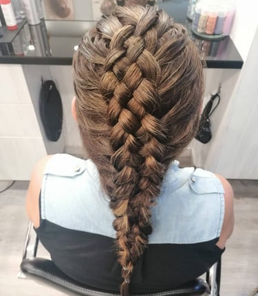 woman with long brunette hair styled in a thick, intricate Dutch braid at a salon.