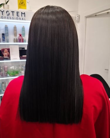 Back view of long, straight, glossy dark brunette hair with a blunt cut at a professional salon.