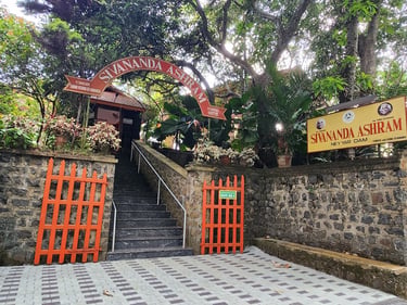 The stone entrance and orange gates of Sivananda Ashram Neyyar Dam yoga retreat in Kerala, India.