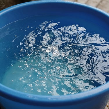 A high-quality photography showing crystal clear, sparkling water filling a freshly cleaned blue water reservoir in a Southeast Asian home setting.