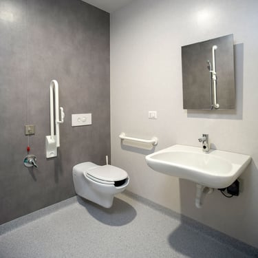 Modern accessible bathroom with wall-mounted toilet, grab bars, and ergonomic sink for disabled users.