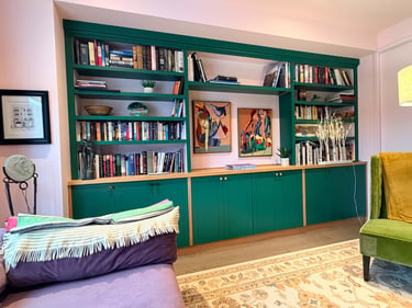 Custom built in wall unit with shelving and cabinetry with uniquely colored finishing details.