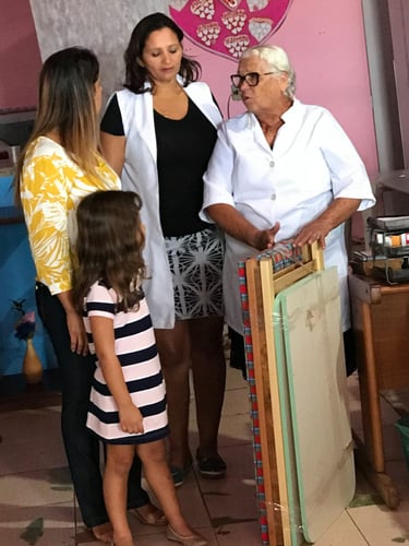 Two healthcare professionals in white coats talking to a woman and young child in a clinic setting.
