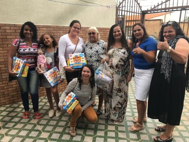 A group of women and children smiling while holding donated toys and games at a community charity event.