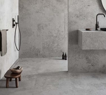 Modern minimalist bathroom featuring grey stone-effect tiles on walls and floors with black matte fixtures.