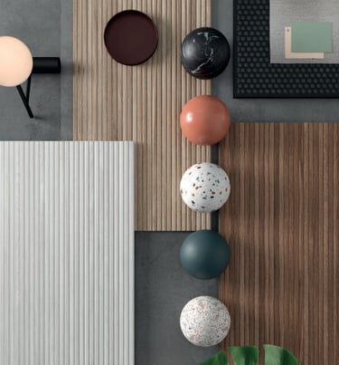 Flat lay of interior design samples featuring wood slat panels, marble spheres, and terrazzo textures.