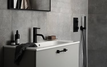Modern bathroom vanity with a matte black faucet, grey tile walls, and a minimalist sink design.