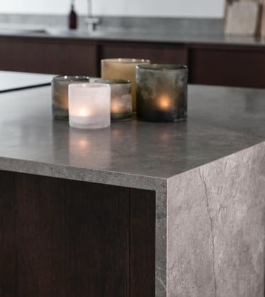 Modern grey stone kitchen countertop featuring lit decorative glass candles.