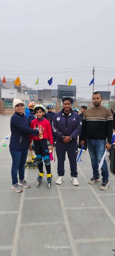 A young roller skater wearing a helmet and safety pads receives a gold medal at an outdoor sports event.