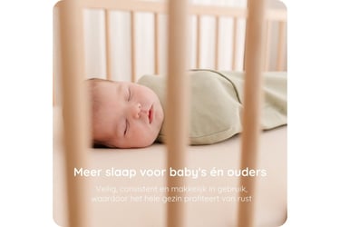 Baby in een Puckababy inbakerzak in een houten ledikant