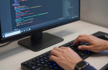 Close-up of a professional in a US software company typing on a high-end backlit keyboard, with lines of clean code reflected in the glass of a navy blue monitor.