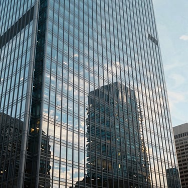 A photograph of a modern glass skyscraper reflecting a clear sky, representing corporate growth and transparency in a North American / US city.