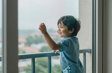 A smiling child safely playing near a balcony window protected by a Keshava safety net. Reassuring, warm, and secure lighting with #EBF2EE and #34495E colors.