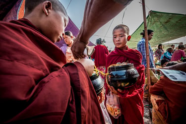 Young novice monks receive food donations in the local market that will be shared at the monastery.