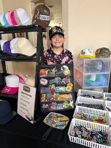 boy smiling behind hat and patch display