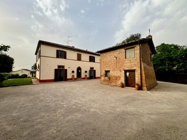 Rustic Italian stone villa and brick farmhouse on a gravel courtyard in Tuscany.