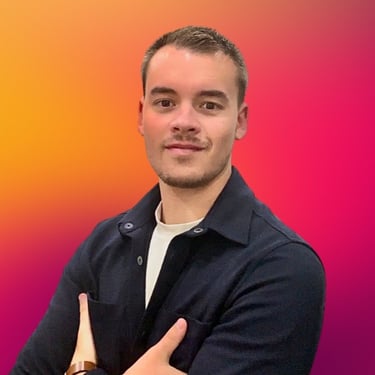 Professional man in a navy jacket posing against a vibrant orange and pink gradient background.