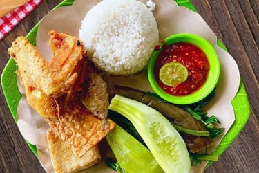 Indonesian Ayam Goreng Lalapan with fried chicken, white rice, sambal, and fresh vegetables.