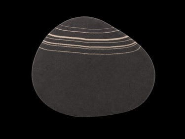 Irregularly shaped dark grey area rug with beige linear stripe patterns on a black background.