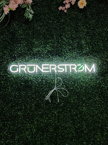 LED Neon Schild „GRÜNERSTROM“ in kaltweiß und grün auf grüner Pflanzenwand