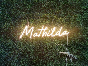 Warm Weißes Neon Schild „Mathilda“ personalisierter LED Neon Schriftzug Name auf grüner Pflanzenwand