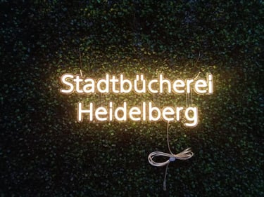 LED Neon Schriftzug Stadtbücherei Heidelberg auf grüner Pflanzenwand – individuelles Firmenlogo als Neon Schild