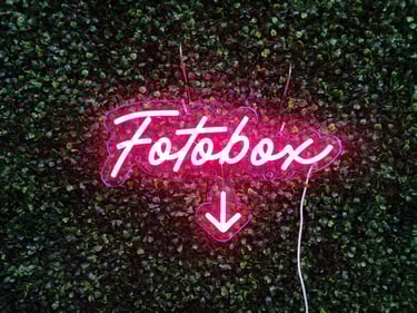 pinkes LED Neon Schild Fotobox mit Pfeil auf grüner Pflanzenwand Event Dekoration