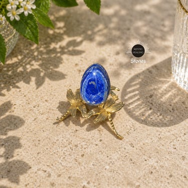 Polished blue lapis lazuli egg crystal displayed on a decorative gold dragonfly stand.