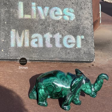 A green malachite elephant crystal figurine displaying natural banding patterns.