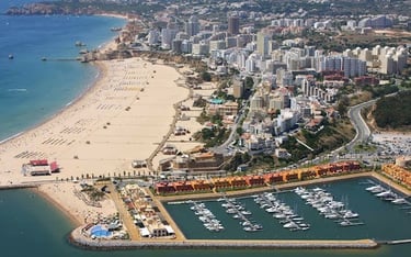 Aerial view of Praia da Rocha beach and Portimao marina with luxury yachts and coastal resorts.