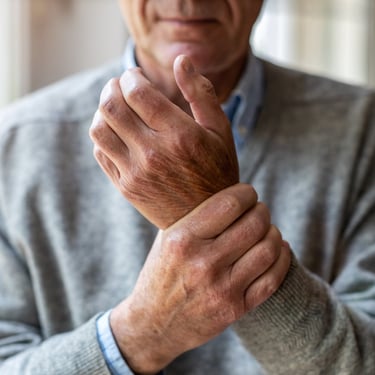 Senior man holding his painful wrist, demonstrating symptoms of arthritis or joint inflammation.