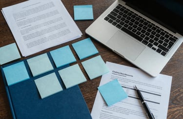 A top-down view of a business brainstorming session with sticky notes, a laptop, and professional documents in shades of medium blue and light gray.