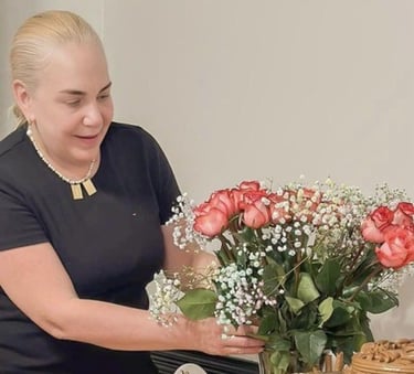 Mujer arreglando un ramo floral de rosas rosadas y flores de velo de novia en un jarrón transparente