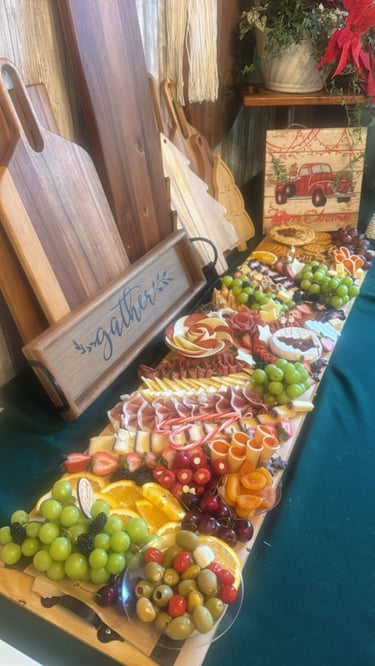 Tabla de charcutería navideña festiva con carnes, quesos, frutas y aceitunas en una mesa de pastoreo