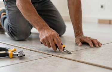 A professional contractor's hands installing modern floor tiles in a North American / Hispanic home, showing precision and professional tools.