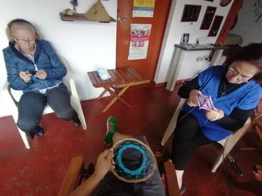 personas tejiendo juntas en costurero, en una sala con puertas de madera y elementos artesanales