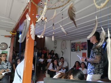 Personas atentas en un conversatorio y taller de fotografía en un salón decorado con afiches y elementos artesanales