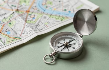 A professional portrait-style photo of a silver compass and a map, used for land acquisition, resting on a table colored in soft sage green.