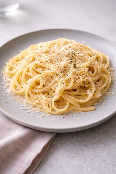 Creamy cacio e pepe pasta with grated pecorino cheese and cracked black pepper.