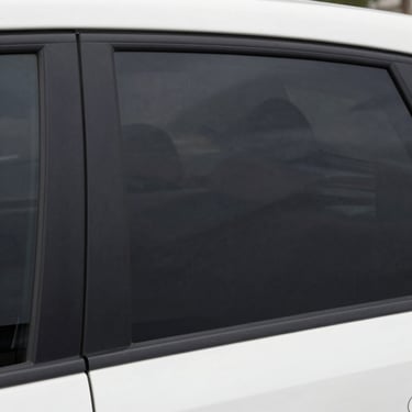 Close-up of a sleek car with freshly applied dark window tint reflecting sunlight.