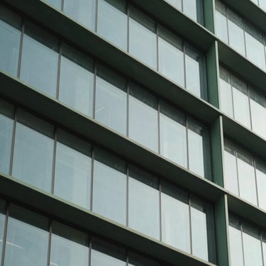 Architectural detail of a sleek building facade featuring glass and steel accents in sage green tones, daylight, professional clean lines.