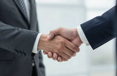 A sharp, close-up photograph of a professional business handshake between two people wearing tailored suits, symbolizing trust and commitment in a US business setting.