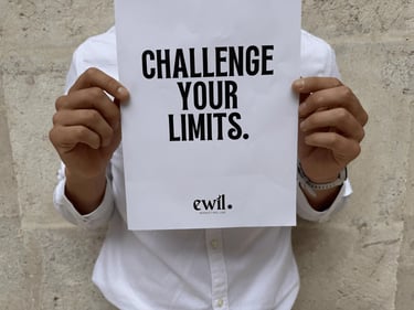 A person holding a motivational sign that says Challenge Your Limits in bold black text.