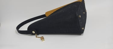 Eco-friendly black cork shoulder bag with gold accents and a natural cork charm.